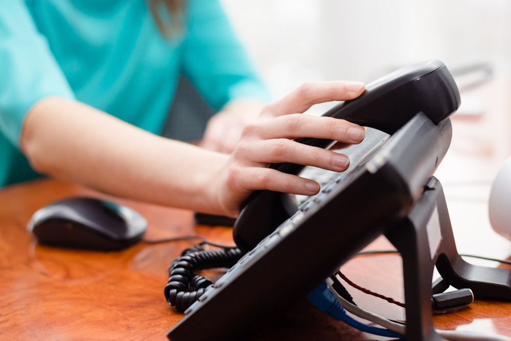 Frau greift zu einem Telefonhörer